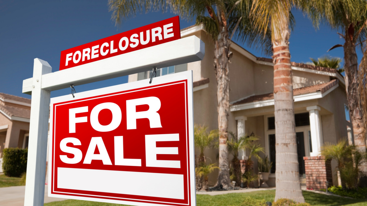 A "Tax Sale" or public auction notice posted on the front lawn or door of a modest single-family home. Another option is a county auction room with bidder paddles raised.